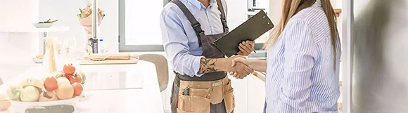 Homeowner shaking hands with a professional handyman in business attire, ensuring customer satisfaction and trust.