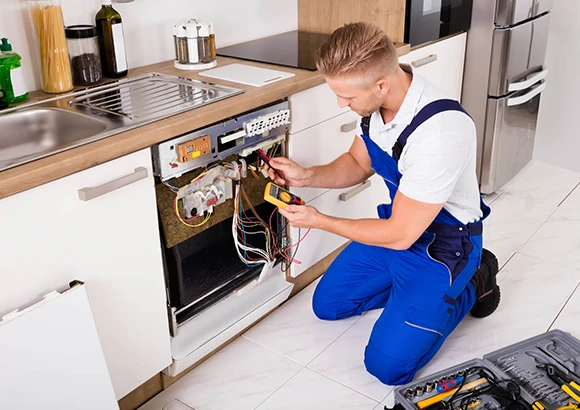 Technician working on plumbing beneath a sink in a kitchen in Miami, FL, emphasizing prompt and professional repair services for common home issues.