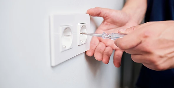 Technician inspecting an electrical outlet for emergency repairs in Delray Beach, FL, emphasizing quick response services for electrical issues.