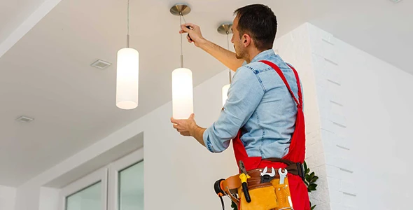 Electrician installing a light fixture in a home in Plantation, FL, highlighting professional lighting installation services to enhance residential spaces.