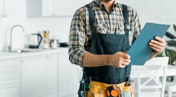 A handyman wearing a plaid shirt and tool belt while holding a clipboard, symbolizing reliable handyman services in Miami, FL.