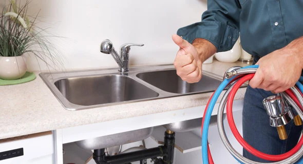 Technician working under a sink to diagnose plumbing issues in a kitchen, emphasizing the importance of reliable residential plumbing services.