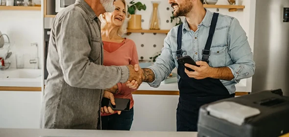 Smiling professional shaking hands with a satisfied customer in a home setting, emphasizing reliability and professionalism in handyman services.